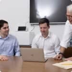 optimia mergers & acquisitions symbol team doing research on computer